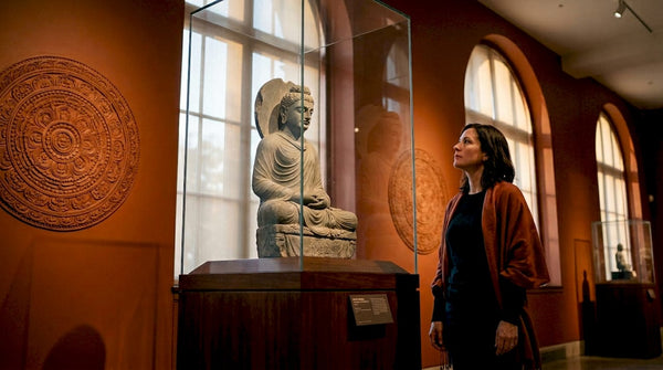 Museum visitor viewing stone Buddha statue