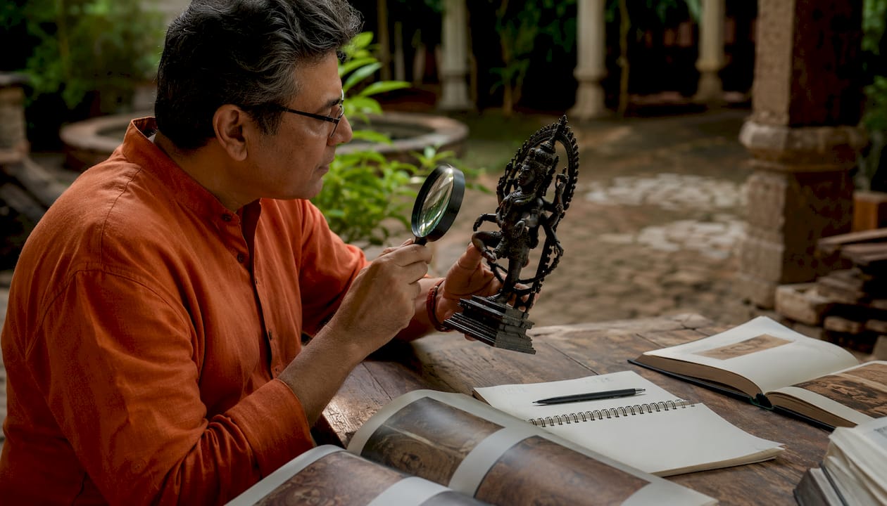Scholar examining Hindu murti sculpture closely